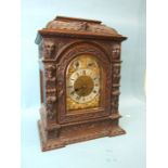 An Edwardian carved oak bracket clock, the arched gilt brass dial with silvered chapter ring, slow/