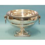A 20th century silver punch bowl with gadrooned rim, two lion's head and ring handles, raised on