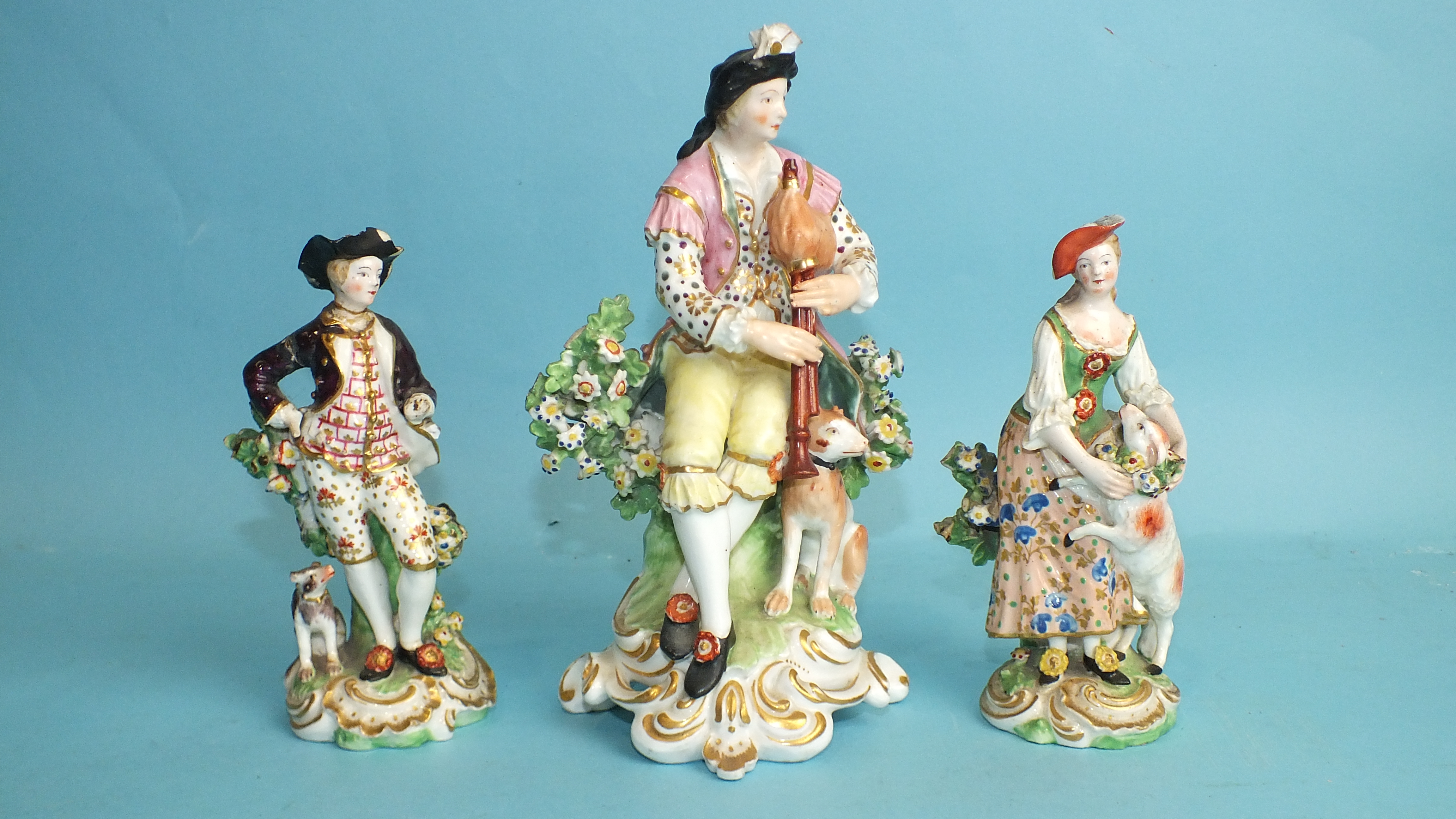 An early-19th century Derby porcelain figure of a seated gentleman playing pipes, 18cm high and a