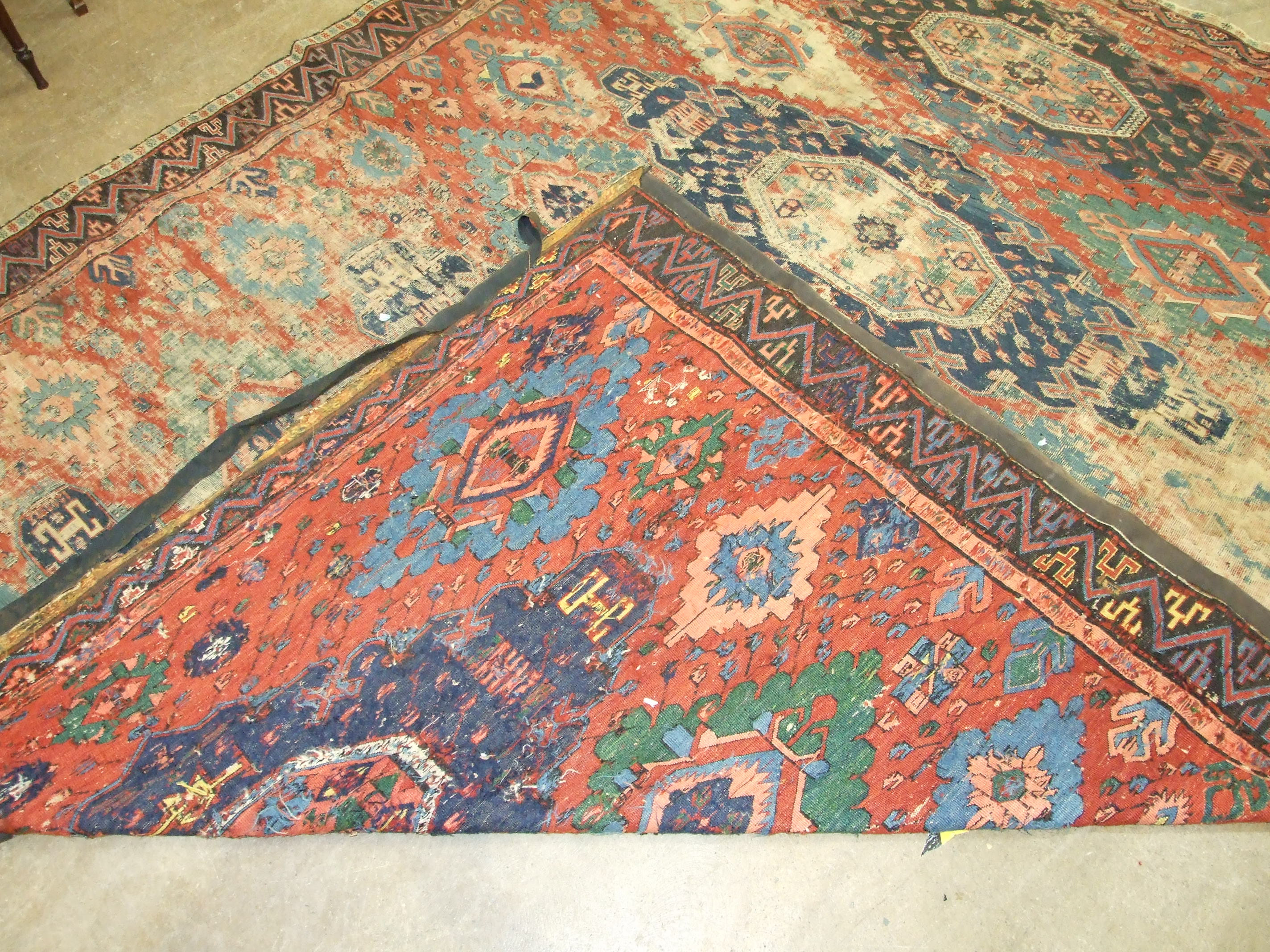 An antique Oriental carpet having four central blue ground lozenges and overall hooked medallions,