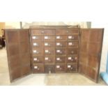 A large antique oak bank of twenty-two drawers enclosed by a pair of panelled doors, 156cm wide,
