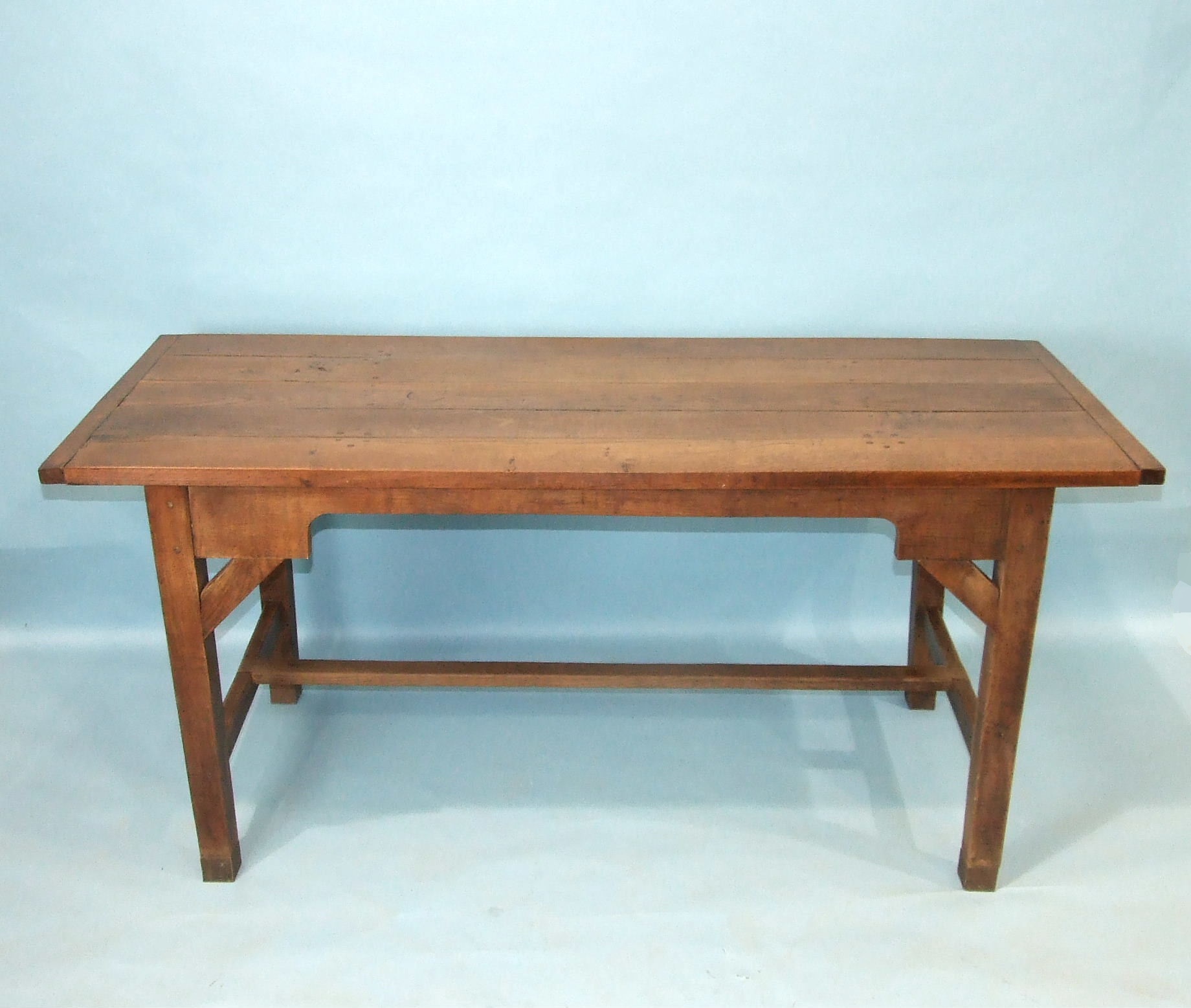 A reconstructed oak farmhouse-style table, the planked top on square tapered legs joined by