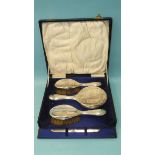 A cased silver dressing table set, comprising mirror, two brushes and a comb mount, all monogrammed,