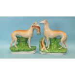 A pair of 19th century Staffordshire pottery figures of greyhounds, each standing, one with a hare