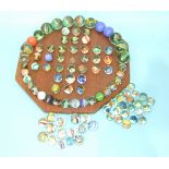 A wooden solitaire board with a selection of glass marbles, including fifteen hand-made marbles, (
