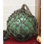 A large green glass fishing float in rope surround, 38cm diameter.