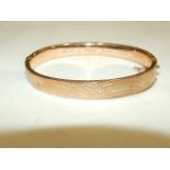 A 9ct rose gold hinged bangle with engine-turned decoration, inscription to inside, 9g, (boxed).