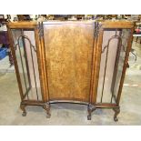 A walnut display cabinet with central concave door, flanked by glazed doors, on claw and ball