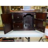 A mahogany smoker's cabinet fitted with two doors opening to reveal two drawers and a pipe rack,