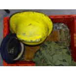 A military tin helmet with camouflage, a Devon Fire Brigade yellow helmet and miscellaneous items.