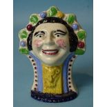 A mid-19th century pearlware mask-head furniture rest, 13cm high, 9cm wide, (manufacturing fault).