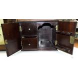 A mahogany smoker's cabinet fitted with two doors opening to reveal two drawers and a pipe rack,