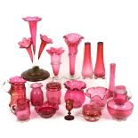 Collection of cranberry glass items including jugs, vases and pot with cover