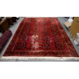 Persian Bokhara style rug, with repeating gul motifs on a red ground within stylised floral borders,