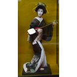 Large Japanese Geisha doll, wearing black kimono and playing shamizen instrument, in glass case