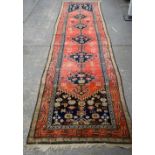 Persian runner with five pole medallion on a red ground with stylised floral and animal motifs,
