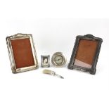 Three silver photo frames, the largest 20 cm high, a silver mounted desk brush and silver fronted