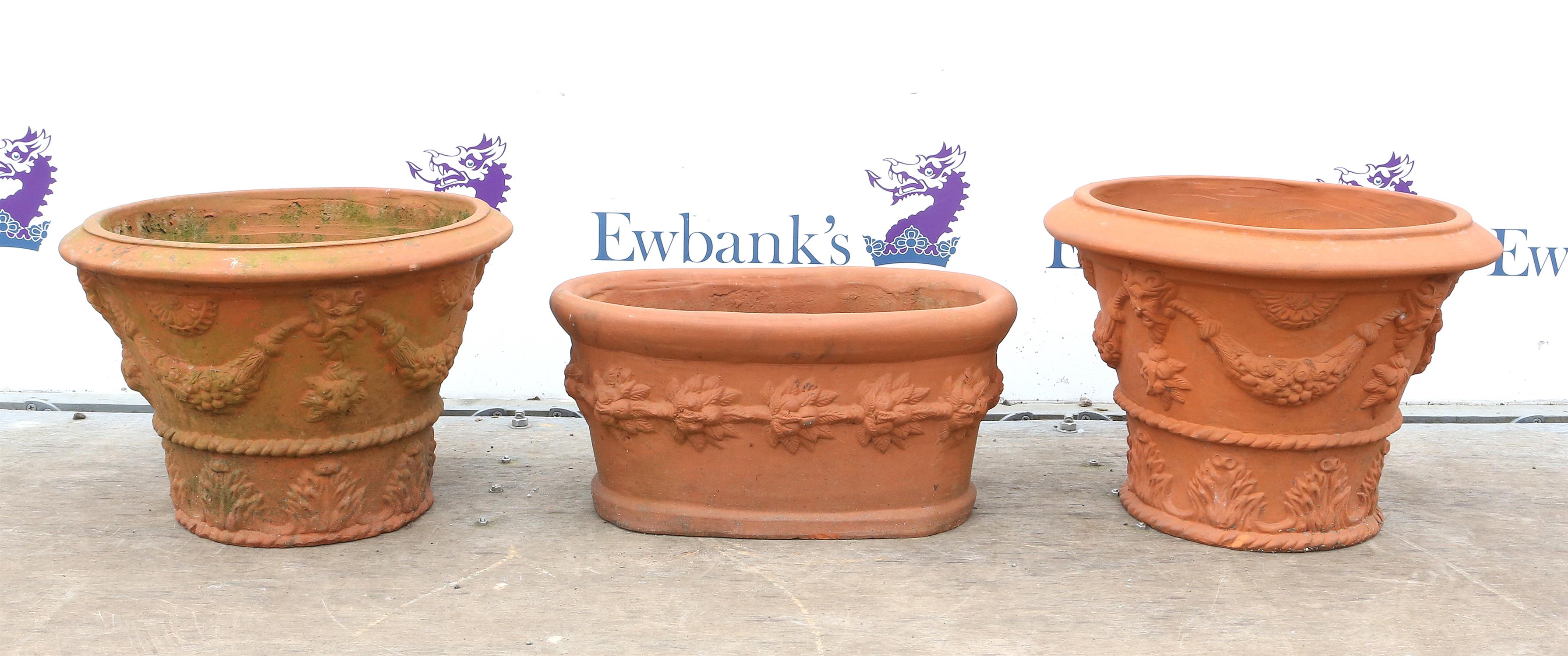 Three terracotta planters, comprising two of circular tapering form with floral swags and masks,