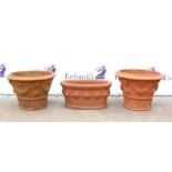Three terracotta planters, comprising two of circular tapering form with floral swags and masks,