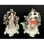 Porcelain bocage figure of a boy playing a pipe, and another of a girl picking flowers,