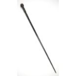 Early 20th century swordstick with carved ebonised handle in tubular black metal sheath, 94cm long,