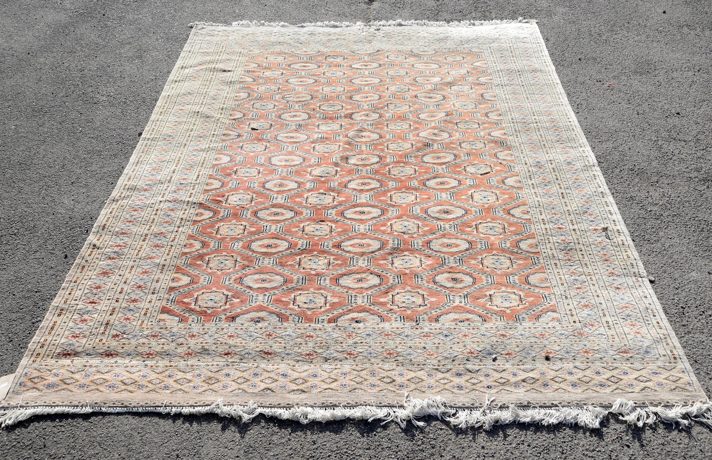 Large Persian carpet with repeating gul motifs on a terracotta ground within stylised floral and