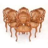 Set of six hardwood dining chairs with floral carved top rails and shaped arms, having caned