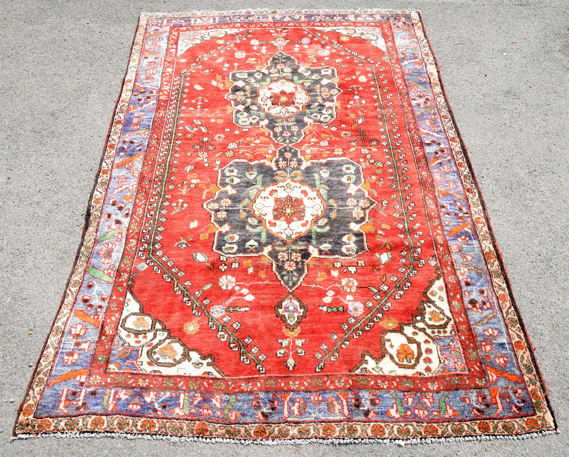 Persian Shiraz village carpet, with twin floral medallions on red ground with vine leaf and floral
