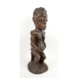 African carved wooden tribal figure, with elaborate coiffure and holding belly on bent legs, H60cm