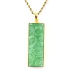 A green glass pendant depicting wheel detailing, in a mount stamped 18 ct, measuring 5 x 2 cm,