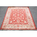 Agra Carpet with scrolling floral design on a red ground within floral borders,180 x 156cm