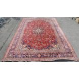 Large Persian carpet, central floral medallion and scrolling floral design on a red ground within