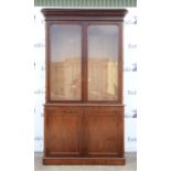 Victorian mahogany bookcase with moulded cornice over two glazed doors revealing four shelves,