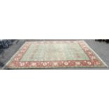 Agra Carpet with repeating floral motifs on a green ground, within a red ground border with floral