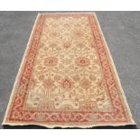 Agra carpet with repeating floral design on a cream ground, within red border with scrolling floral