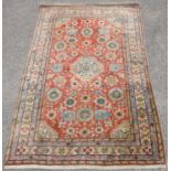 Persian red ground rug, with central floral medallion and floral motifs on a red ground,