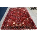 Persian Heriz carpet, central floral medallion on a red ground within stylised floral border,