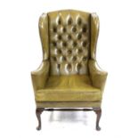 Reproduction green leather wing back armchair on cabriole legs untied by stretchers,