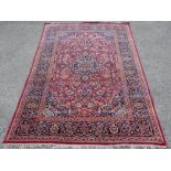 Persian burgundy ground rug, central medallion and scrolling floral design within scrolling floral