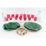 Fourteen cranberry drinking glasses, two Rosenthal figures, four green leaf moulded plates and a