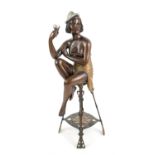 1920s cast metal figure of a semi-nude lady, holding a cup and seated on an Art Nouveau style stool,