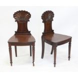 Pair of 19th century mahogany hall chairs, with shell and C-scroll carved backrests, on turned legs,