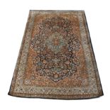 Persian part silk rug, central floral medallion and scrolling floral design on a dark blue ground,
