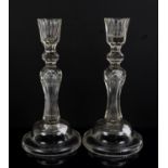 Pair of early 20th century glass candlesticks with faceted decoration on stepped round feet,