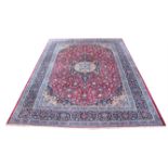 Persian Meshad carpet, central floral medallion and flowerheads on a red ground within blue ground
