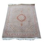 Persian rug with central medallion and repeating motifs within pink ground scrolling floral border,