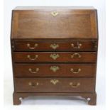 George III oak bureau, the sloping fall enclosing pigeonholes and drawers, over four long graduated