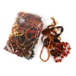 A bag of beaded jewellery, including heat treated amber necklaces, faux coral bead necklaces,