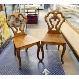 Pair of Victorian oak hall chairs, the pierced backs carved with a crest over solid backs and