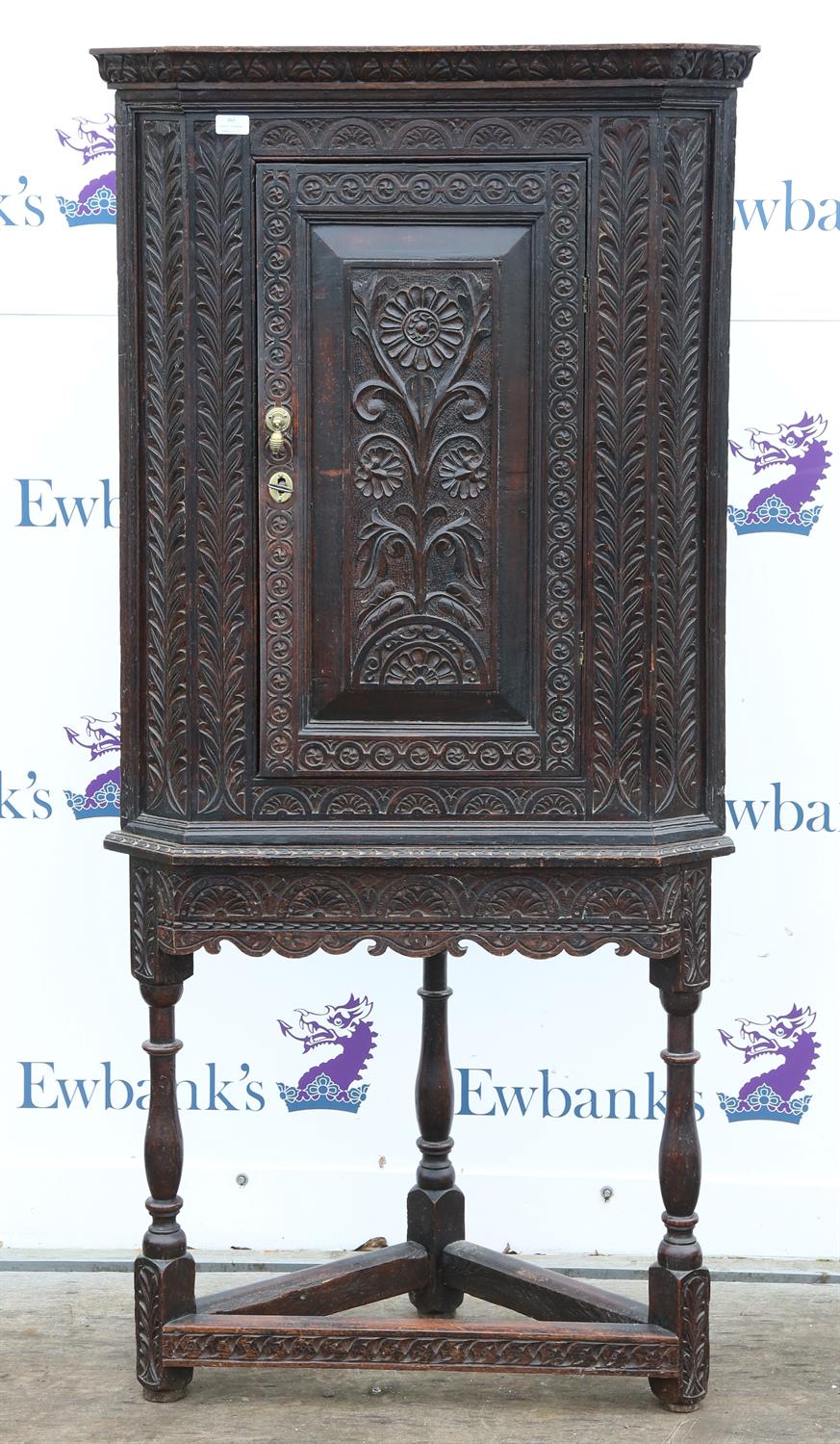 Carved oak corner cupboard on stand, with foliate, floral and lunette carving, on turned supports,